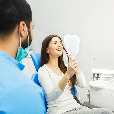 lady in dentist chair looking in hand mirror