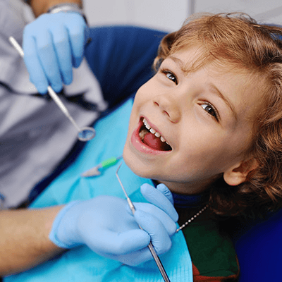 young boy smiling in dentist chair